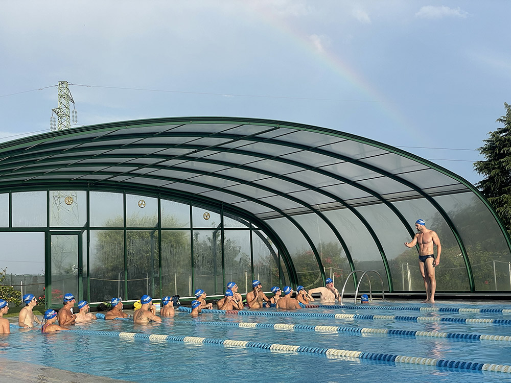 Allenamento di gruppo in piscina con istruttore a bordo vasca